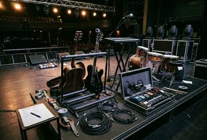Escenario iluminado mientras una banda toca ante público en una sala